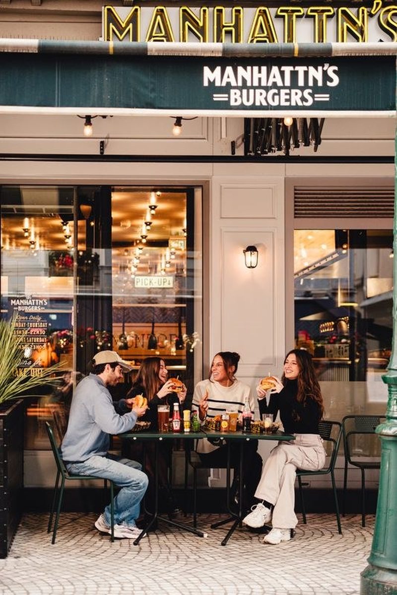 La terrasse et l'entrée du restaurant, sous l'enseigne Manhattn's Burgers